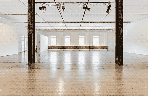 photograph of The Lab main space, which is a large empty room with a wood floor, and two steel pillars